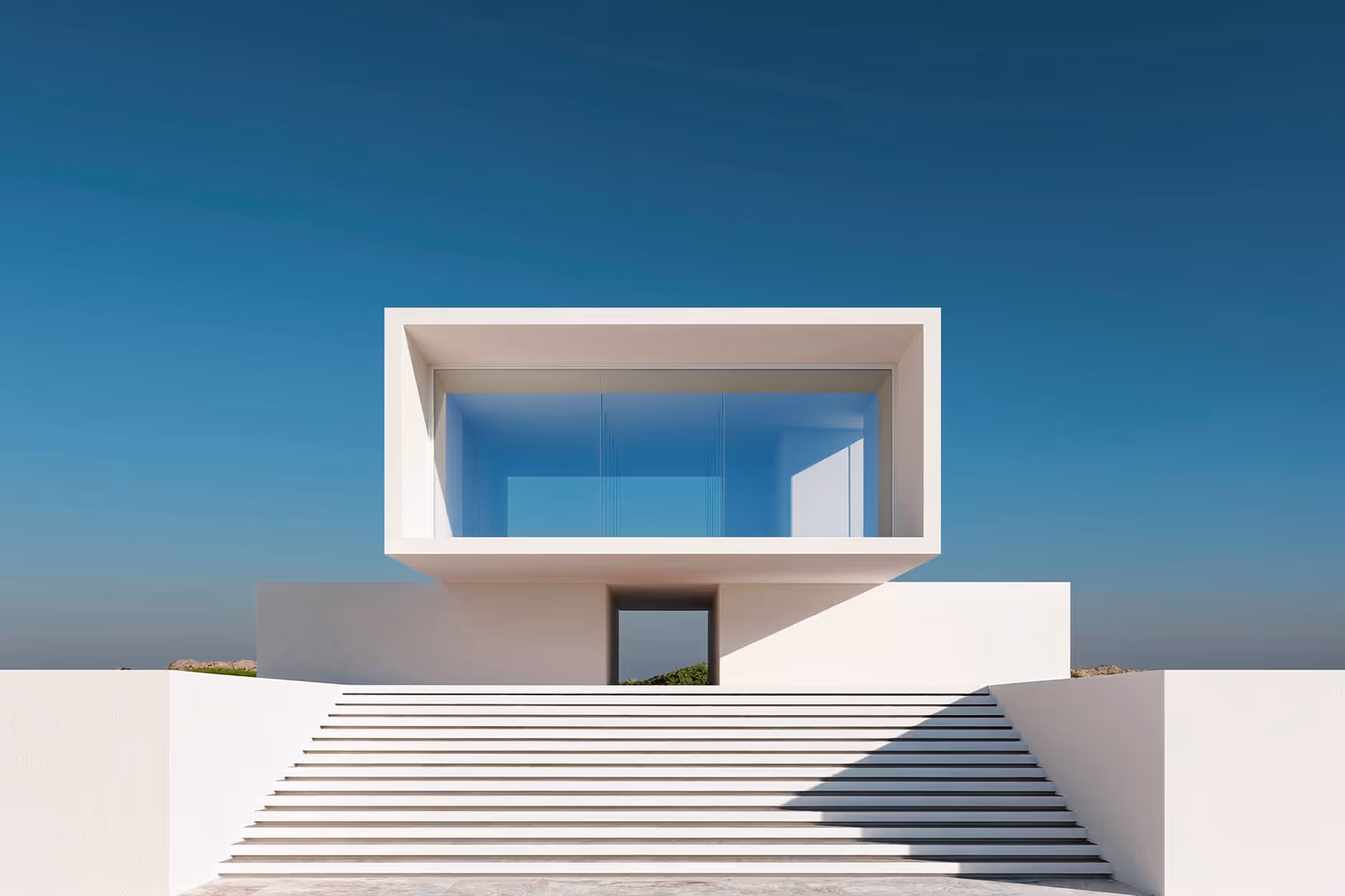 Façade blanche d'une maison contemporaine composée d'un volume rectangulaire ouvert posé sur un socle bas, accessible par un large escalier à marches régulières, sur fond de ciel bleu uniforme.