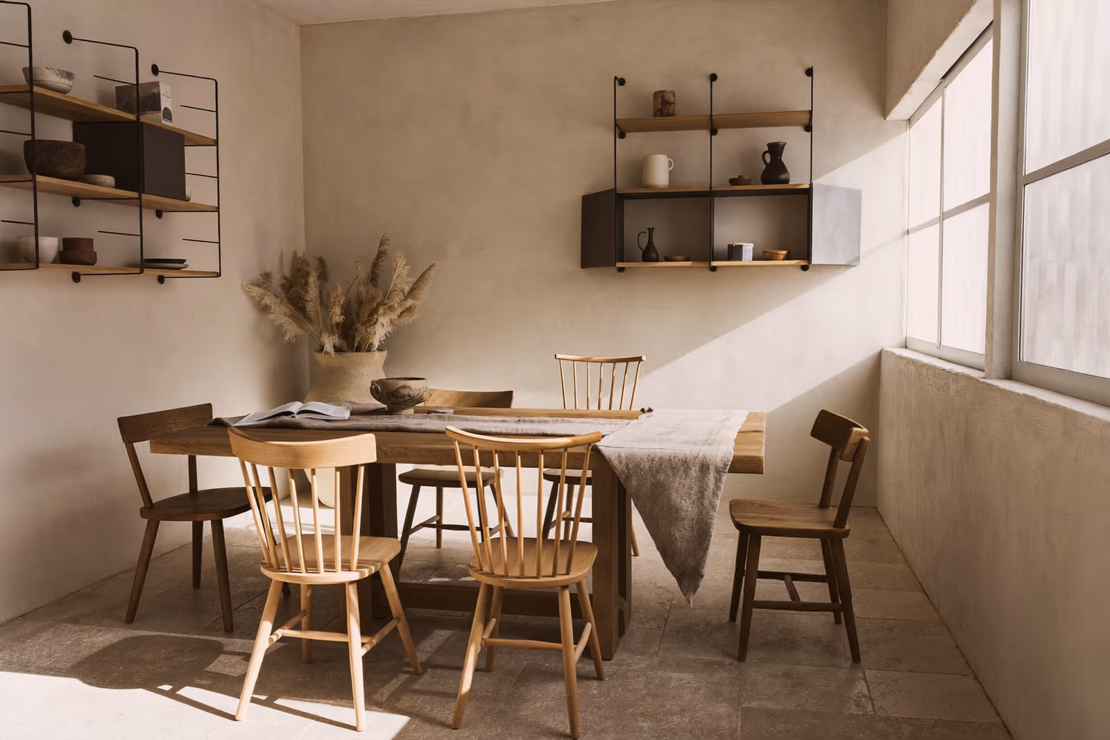 Coin repas Japandi : table et chaises en bois, étagère murale, lumière douce filtrée.